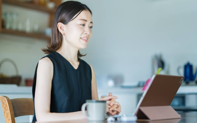 女性がタブレットでオンラインセミナーを受けている様子